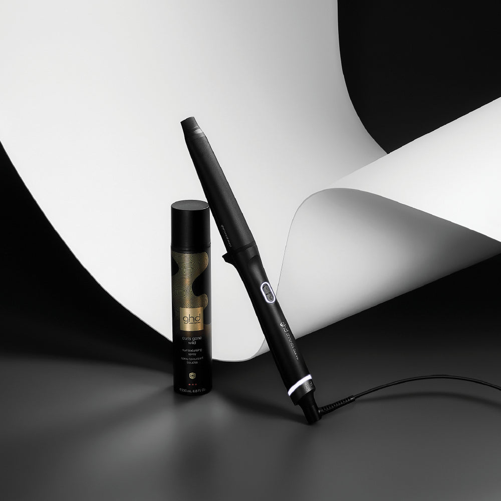 Hair straightener and hair product bottle on a black and white background