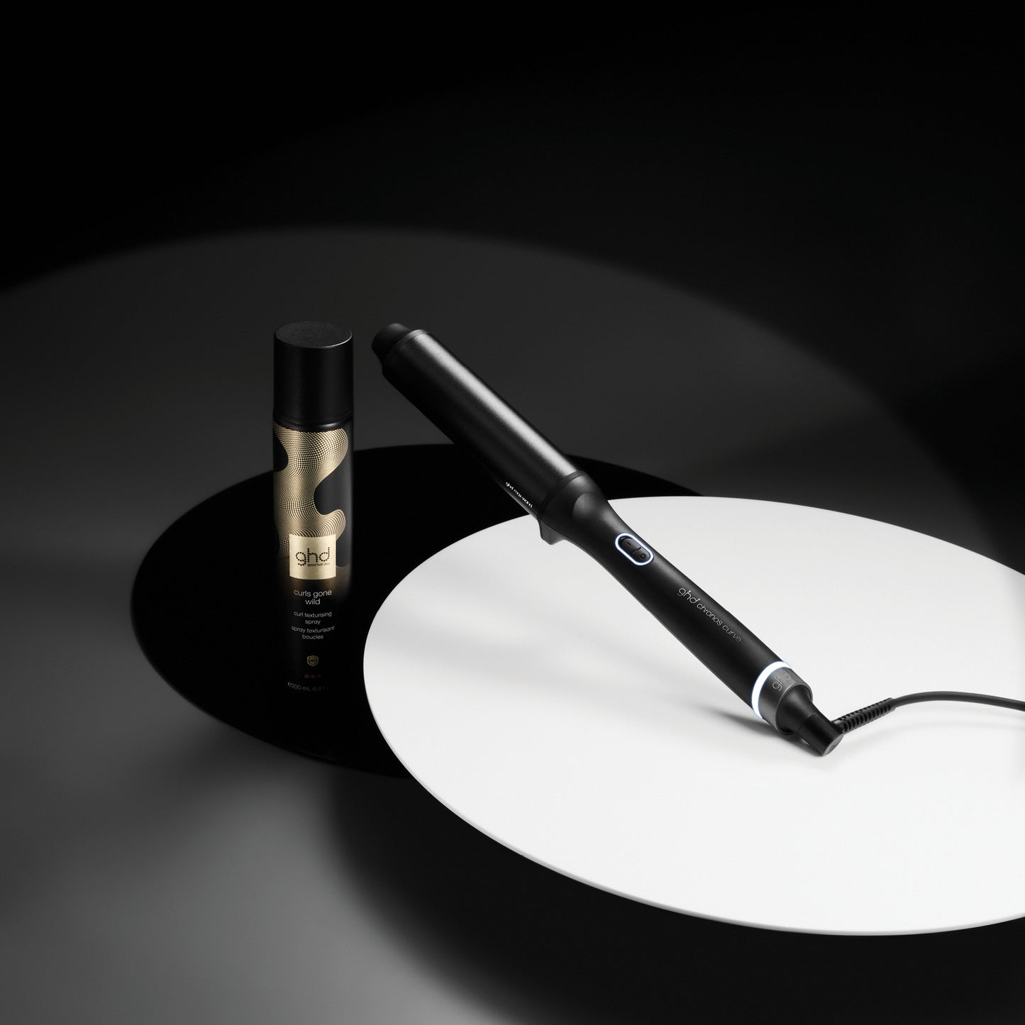 Hair straightener and bottle on a dark background